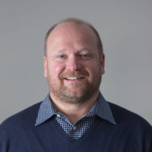 A man with a beard showing leadership by smiling for the camera.