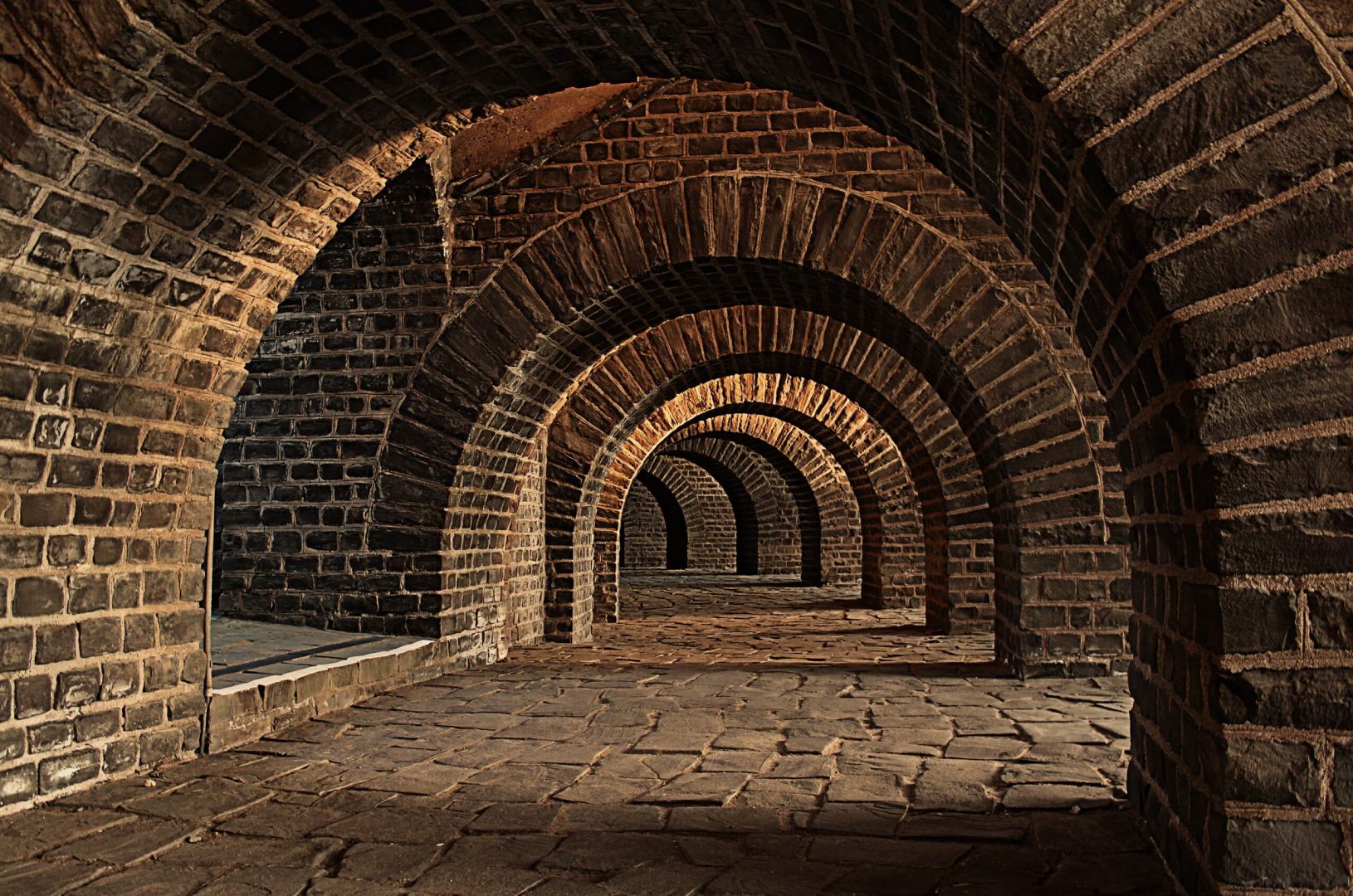 A hallway with arches in the middle of a brick wall.